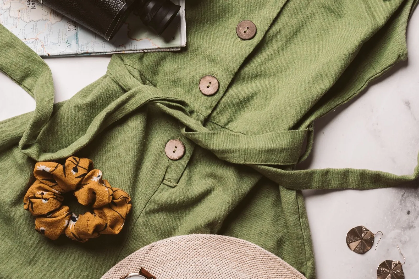 A notebook, reusable bottle, sun hat and light layers prepared for a day out